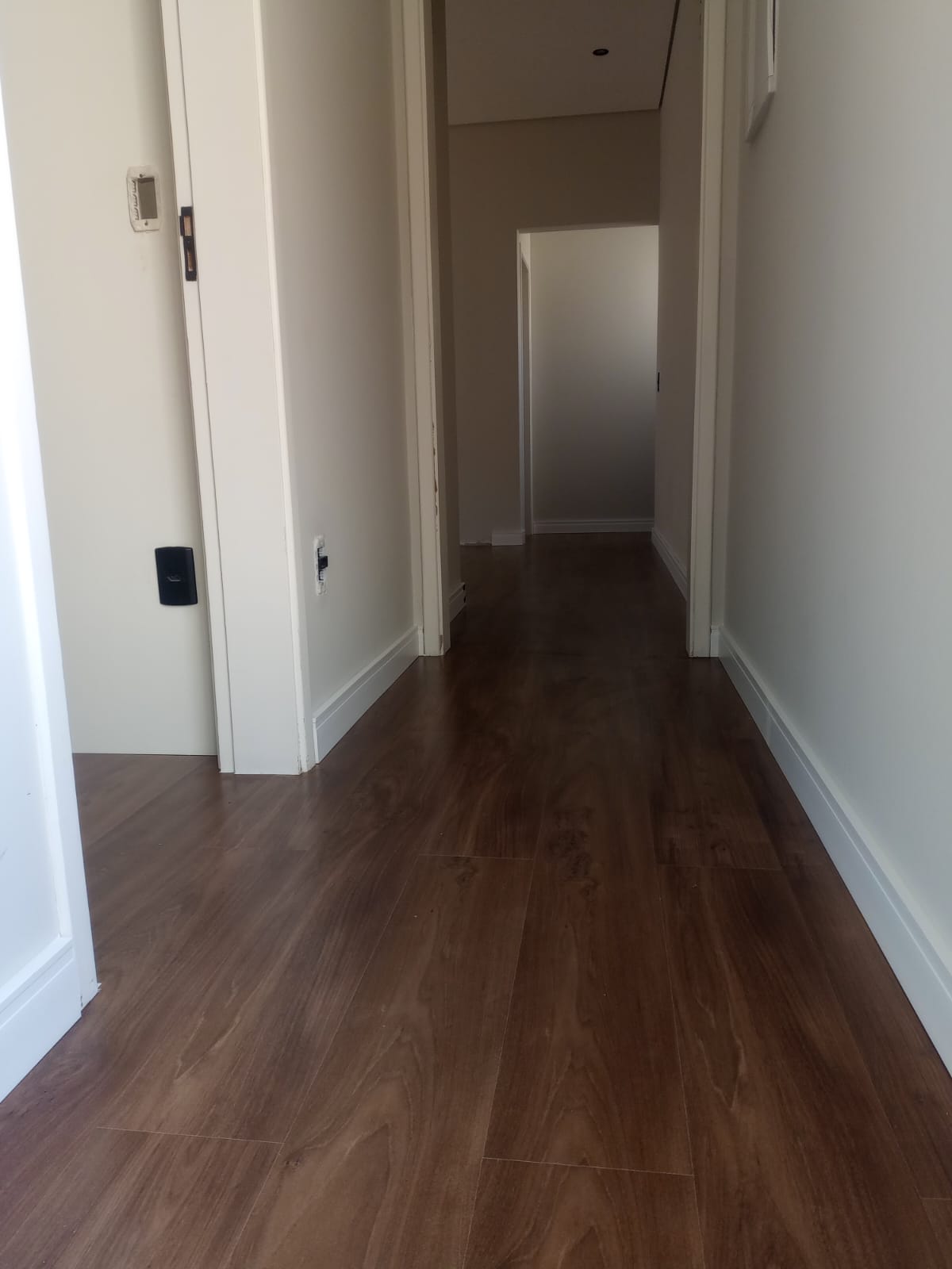 Piso amadeirado escuro com rodapé branco